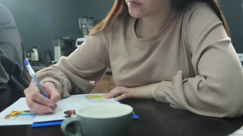 Woman completes form detailing coffee preferences. Female coffee shop employee takes test to enhance qualifications near cup of cofee slow motion