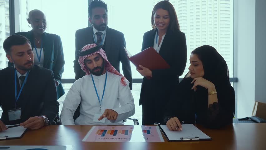 Multicultural business team with arab professionals engaging in video conference, discussing strategy with ceo on large screen in modern conference room.