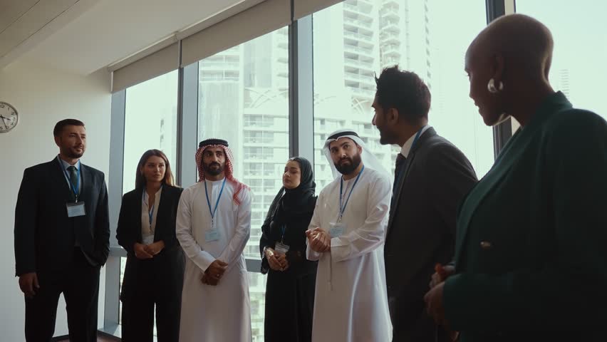 Multicultural businesspeople wearing suits and traditional clothing stand together in a modern office, embodying teamwork and cultural diversity. - Powered by Shutterstock - Get 15% off with code: PIKWIZARD15