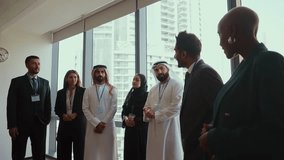 Multicultural businesspeople wearing suits and traditional clothing stand together in a modern office, embodying teamwork and cultural diversity. - Powered by Shutterstock - Get 15% off with code: PIKWIZARD15