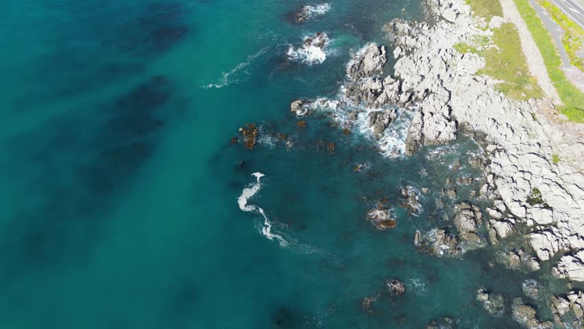 Aerial drone footage of clear blue ocean water with rocky shoreline. Shot near Kaikoura, New Zealand.
