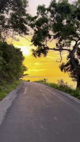 Scenic Coastal Road at Sunset in Bali, Captured from a Moving Motorcycle

