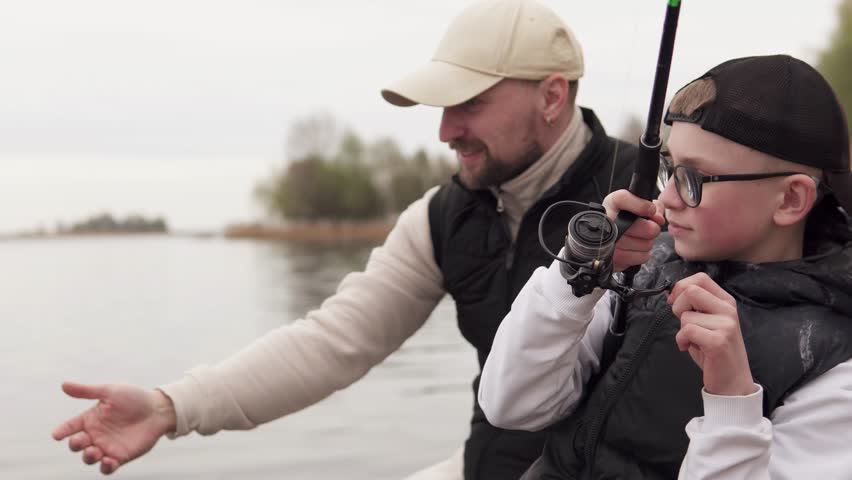 Father and son fishing on a wooden pier. Father teaching his child to fish. Fatherhood concept.