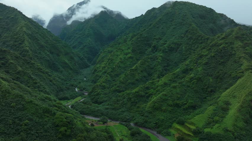 Tahiti French Polynesia Teahupoo aerial drone raining fog mountain peaks river morning grey gray season wet green Point Faremahora village town South Pacific Mount Tohivea island backwards pan up