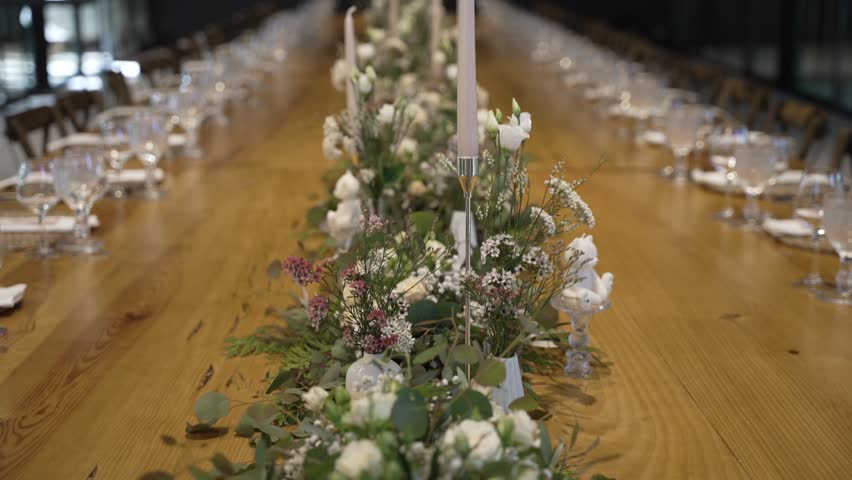Elegant dining table setup with floral centerpieces and candles for a formal event.