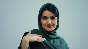 Studio portrait of an attractive young muslim woman wearing a traditional dark green hijab, posing on a white background, looking at camera and smiling. - Powered by Shutterstock - Get 15% off with code: PIKWIZARD15