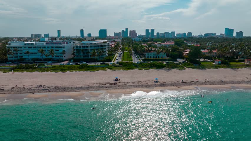 West Palm Beach, Royal Palm Way aerial hyper lapse. Beach to luxury street with downtown skyline in background at sunset.