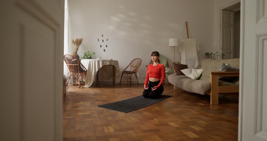 Girl in orange sweater doing yoga and getting into cobra pose on gym mat at home. Zoom in sporty girl doing yoga at home