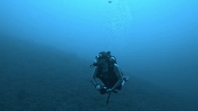 Footage of a scuba diver holding an underwater camera, exploring the deep blue ocean and capturing marine life. - Powered by Shutterstock - Get 15% off with code: PIKWIZARD15