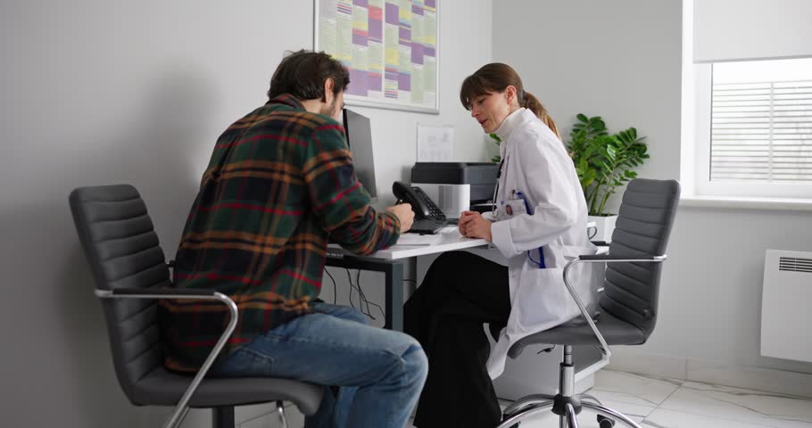 Guy in a plaid shirt fills out a questionnaire at a girl doctor office in a hospital. Guy makes a note on a questionnaire during the start of an examination in a hospital