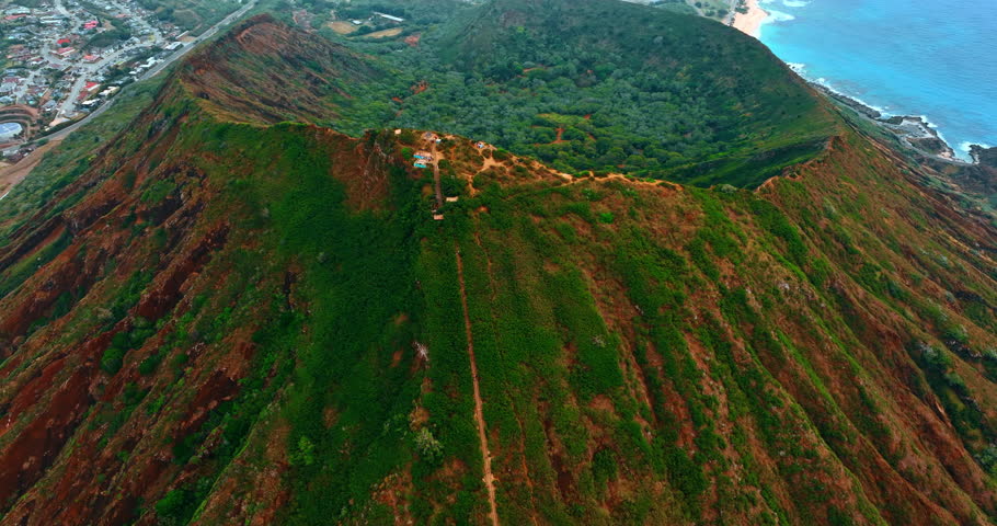 Approaching the top of Koko Head Carter. Jaw-dropping scenery of the crater inside from drone. Cityscape of Honolulu, Hawaii, USA at backdrop. Top view.