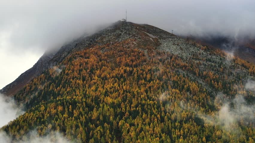 Moody fog Swiss Alps peak Saastal Saas Fee Switzerland aerial drone foggy cloudy rainy Larch forest beautiful Fall Autumn Swiss Alps mountain peaks glacier valley Zermatt The Matterhorn left circle