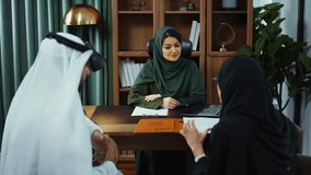 Emirati businesswoman in traditional attire leads a meeting with two  colleagues, gesturing and engaging in conversation across a desk in a modern office setting. - Powered by Shutterstock - Get 15% off with code: PIKWIZARD15