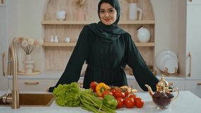 Elegantly dressed muslim woman in dark green abaya standing in modern kitchen, displaying range of emotions while surrounded by fresh ingredients and traditional elements - Powered by Shutterstock - Get 15% off with code: PIKWIZARD15