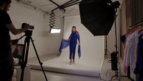 Daily lifestyle concept. Young adult woman spending time at studio, woman model in fancy outfit taking part in a photoshoot in professional studio with photographer and assistants, posing at camera. - Powered by Shutterstock - Get 15% off with code: PIKWIZARD15