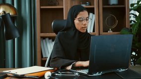 Young muslim doctor woman wearing traditional headscarf sitting at desk in office making video call with patient explaining diagnosis and writing notes on clipboard. - Powered by Shutterstock - Get 15% off with code: PIKWIZARD15
