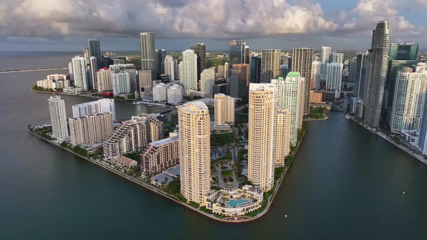 Downtown Miami skyline and Brickell Key. High aerial orbit during morning sunrise light. Drone establishing shot of Miami, Florida high rises and Biscayne Bay, Miami River, Atlantic Ocean.