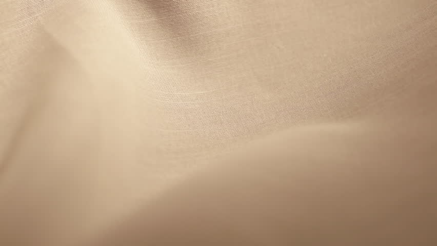 Single gold engagement ring sliding downwards over a tan-colored cotton fabric.