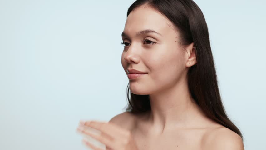 Back view of a young female adult adjusting hair and preparing for going out in a beauty concept a plain background.