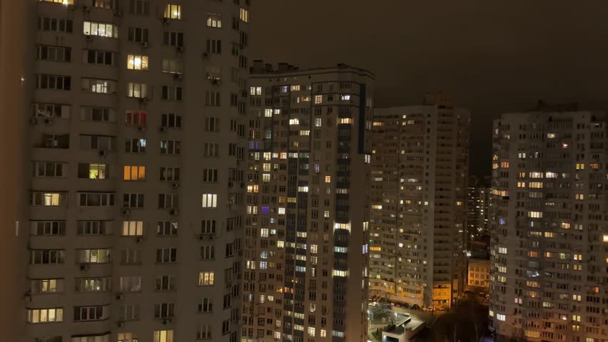 Multi story apartment buildings in modern housing estate of big city, top view against the cloudy sky at night while panning
