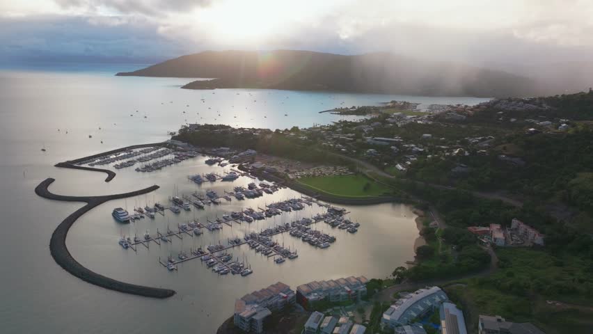 Port Airlie Beach Bay Lagoon Coral Sea marina jetty yachts sailboats aerial drone cloud layer mist sunrise morning rain clouds heart of Great Barrier Reef Whitsundays Whitehaven circle left motion
