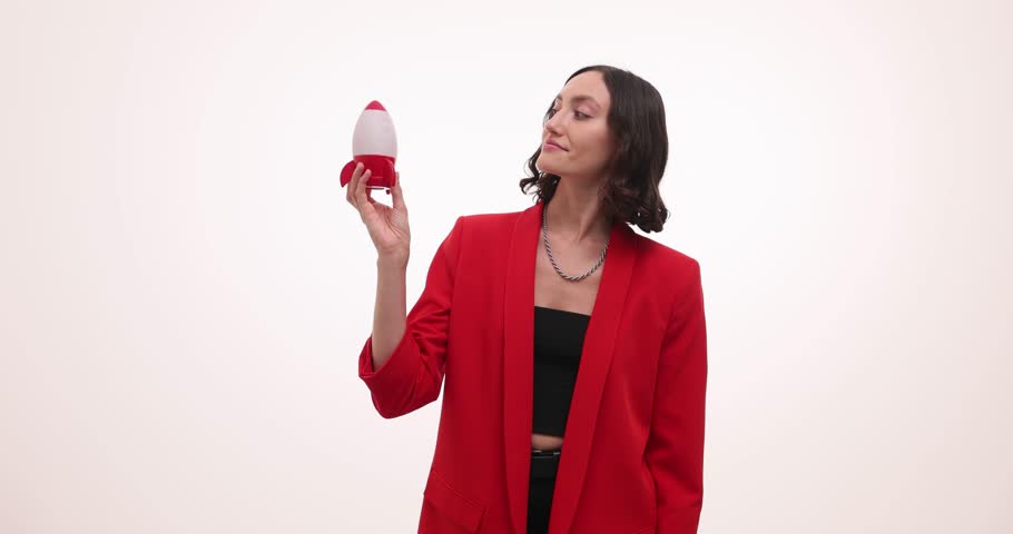 Happy woman holds small toy rocket and points upwards with finger with hopeful and suggestive expression. Actions imply concept of launching to space