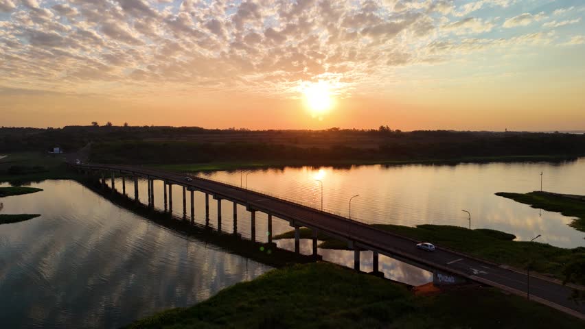 Aerial view of cinematic sunset on the Paraná River. bridge over the Arroyo Mártires in Posadas, Misiones, Argentina. Sustainable solar energy.