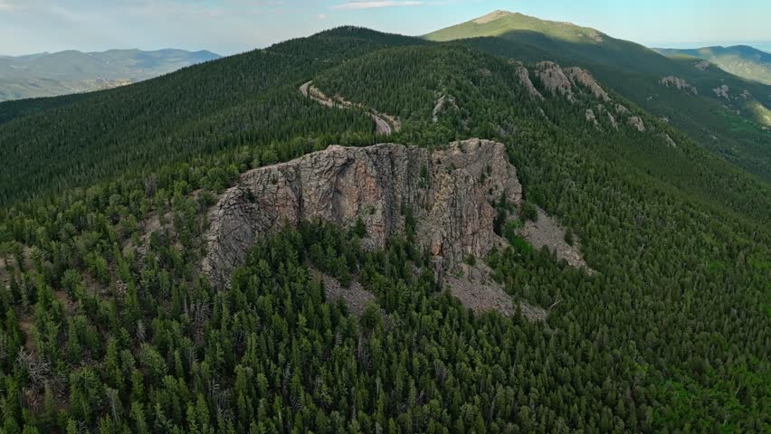 Rock escarpment rises above continental divide and evergreen forest along Mount Blue Sky scenic byway