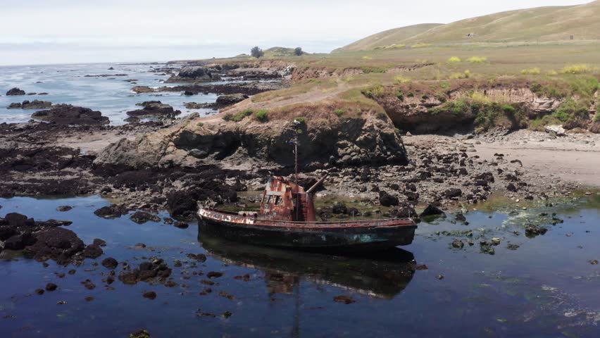 Close-up push-in aerial shot of a beached shipwreck along the coast of Cayucos in Morro Bay, California. 4K