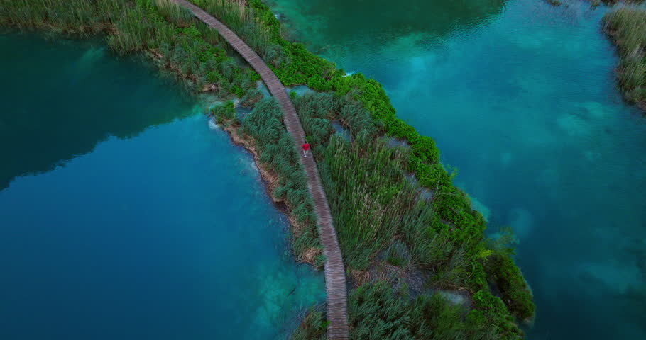 Traveler Walking On Wooden Walkway Between Lakes In Early Morning. Plitvice Lakes National Park, Croatia. aerial shot