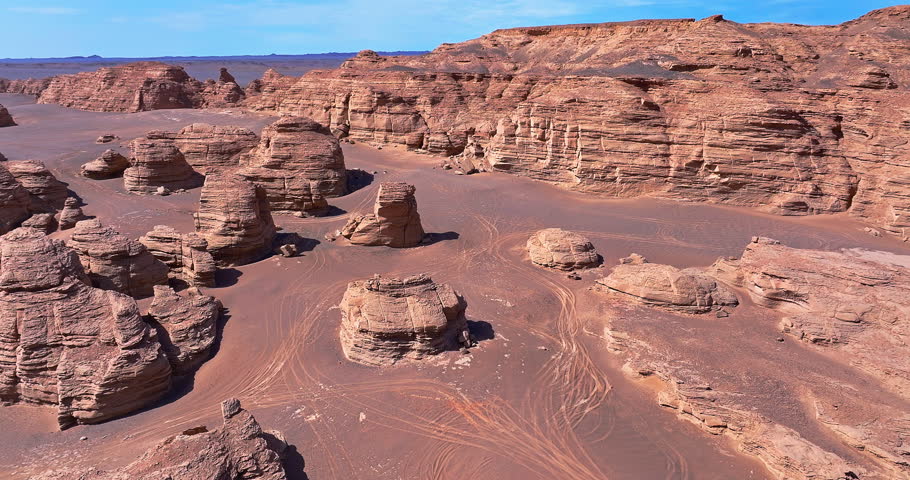 Aerial view of unique yardang geological formations scattered across a vast red desert landscape under blue sky. Famous Dahaidao no man