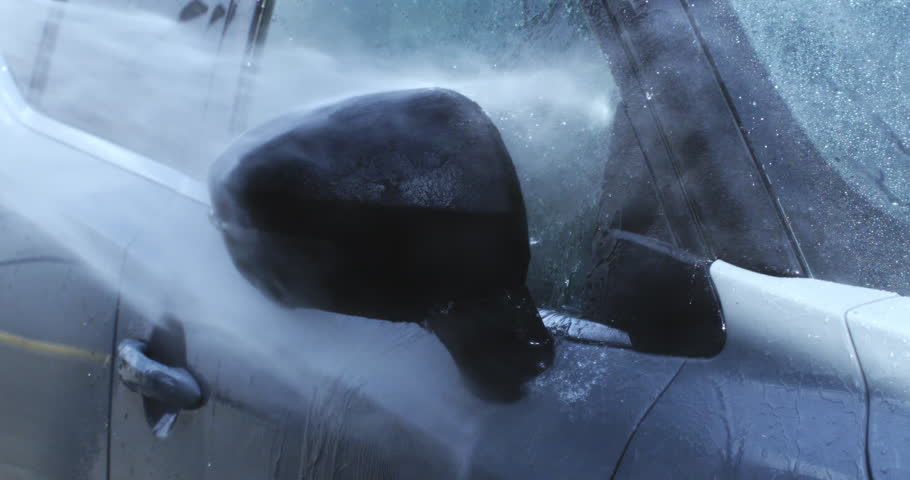 Super Slow Motion Close Up of High-Pressure Water Cleaning Black Car Side Mirror During Car Wash. Powerful Jet of Water Splashes Over Glass and Paint for Deep Exterior Vehicle Maintenance at 1000 fps