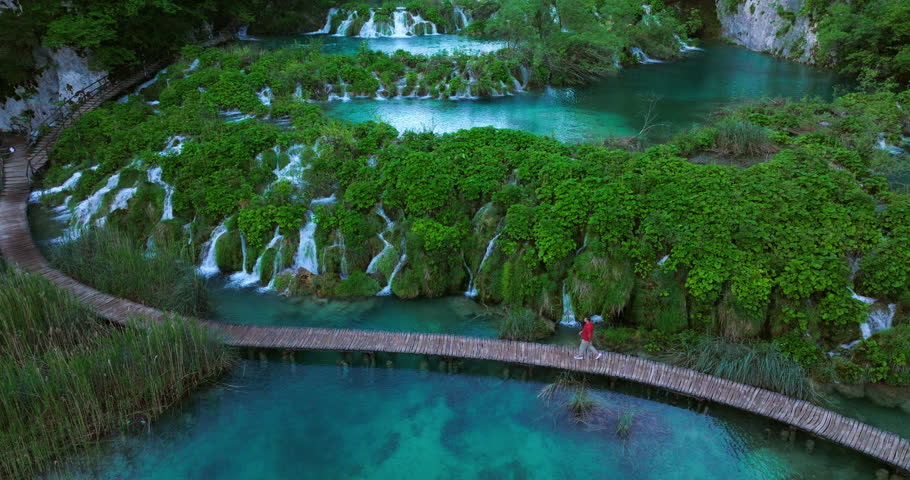 Man On Boardwalk Of Plitvice Lakes National Park Trekking In Croatia. Aerial Shot