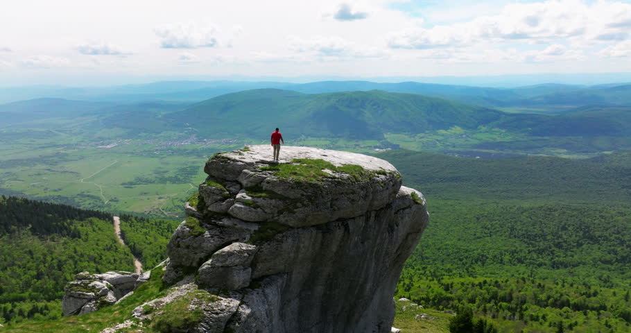 Fearless Traveler Walking On Top Of Rock Formation On Pljesivica Mountain In Croatia. aerial orbiting shot