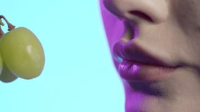 woman eating white grapes in mouth close-up, girly nail polish and red lipstick lips on blue background - Powered by Shutterstock - Get 15% off with code: PIKWIZARD15