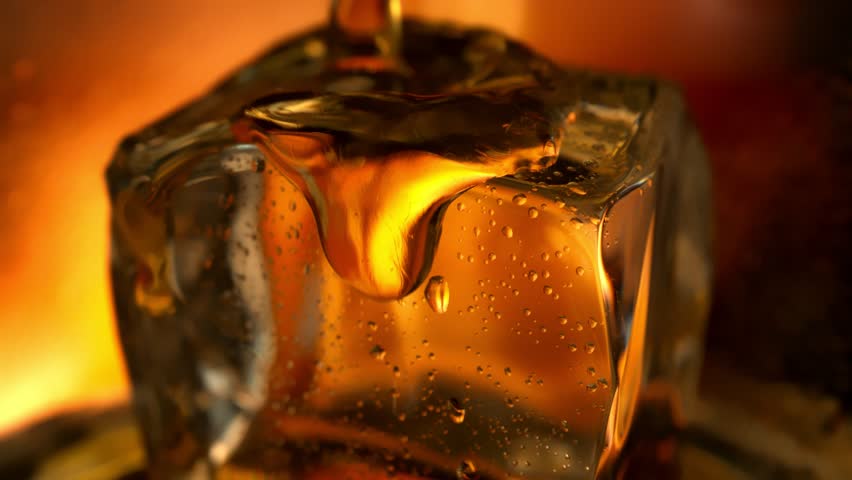 Super Slow Motion Detail Shot of Pouring Whiskey on Ice Cube in Glass at 1000fps.