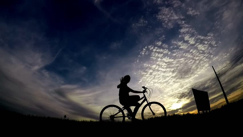 silhouette of a man with a bicycle at sunset