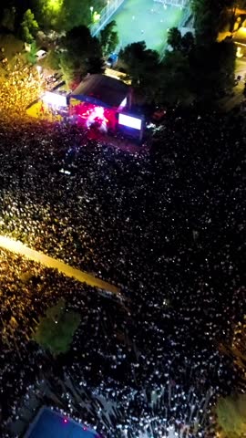 Vertical video at the concert - High quality aerial view of people having fun at the concert, concert stage and stage lights, lasers taken by drone