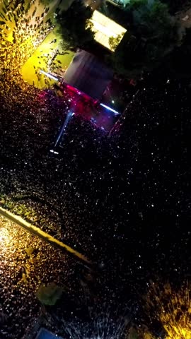 Vertical video at the concert - High quality aerial view of people having fun at the concert, concert stage and stage lights, lasers taken by drone