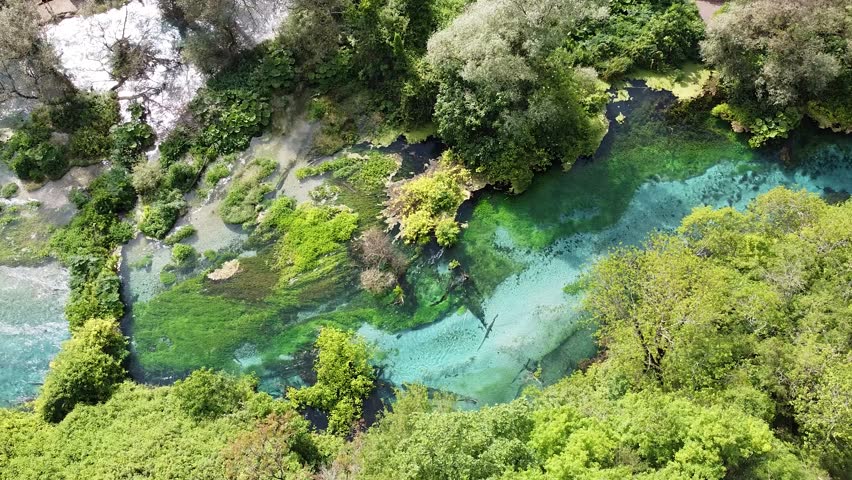 Aerial view of the Blue Eye, a natural spring in Albania, showcasing its vibrant blue and green hues amidst lush greenery.
