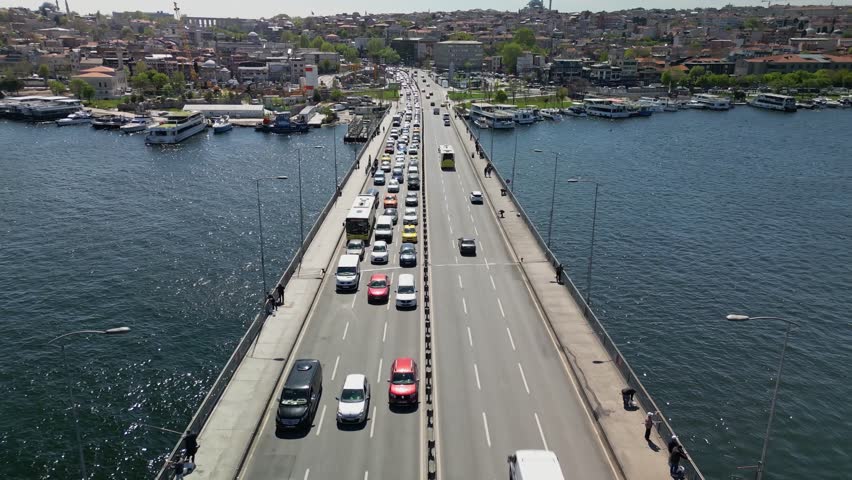 Elevated drone perspective showing Istanbul's bridge with cars and boats. Rising motion reveals the city's layered history and its vital transportation routes