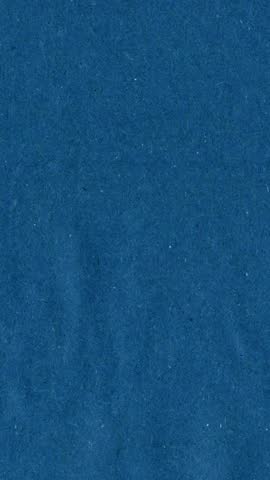 Blue kraft paper noise texture vertical stop motion video. Old page overlay effect background loop animation. Vintage paper texture with crease, stain, grain, dust particles. Empty animated backdrop 