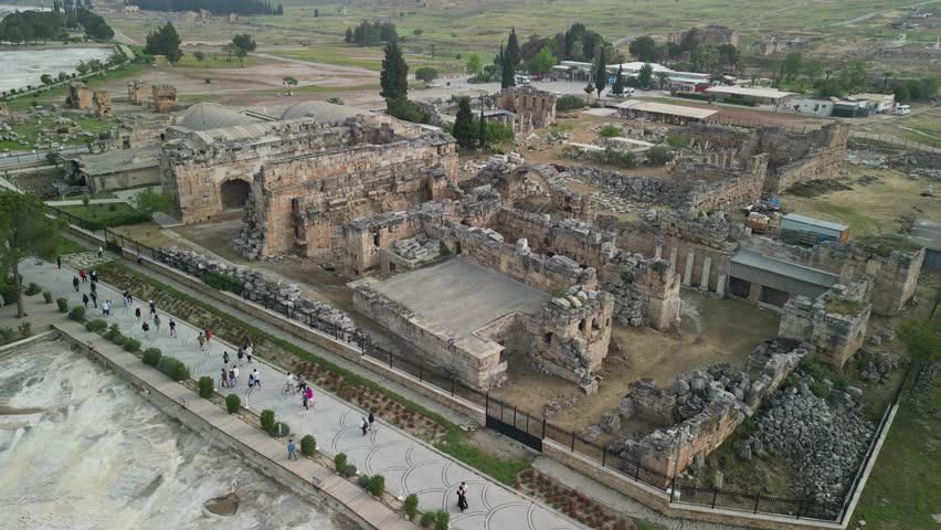 Drone view of ancient Hierapolis ruins in Pamukkale, Turkiye. Semicircular layout shows Roman architecture. Historic site in Turkey. Famous Greco-Roman archaeological heritage.