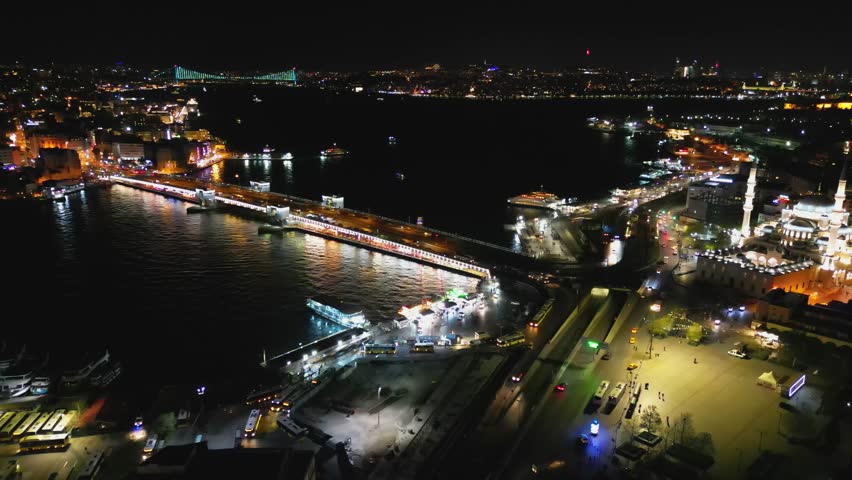 Night aerial view in a half-circle over Galata Bridge. Lights reflect off the Bosphorus. Istanbul
