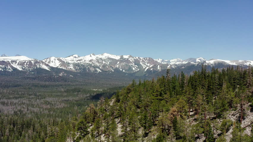 The sierra nevada mountains with snow-capped peaks and lush green forests, aerial view
