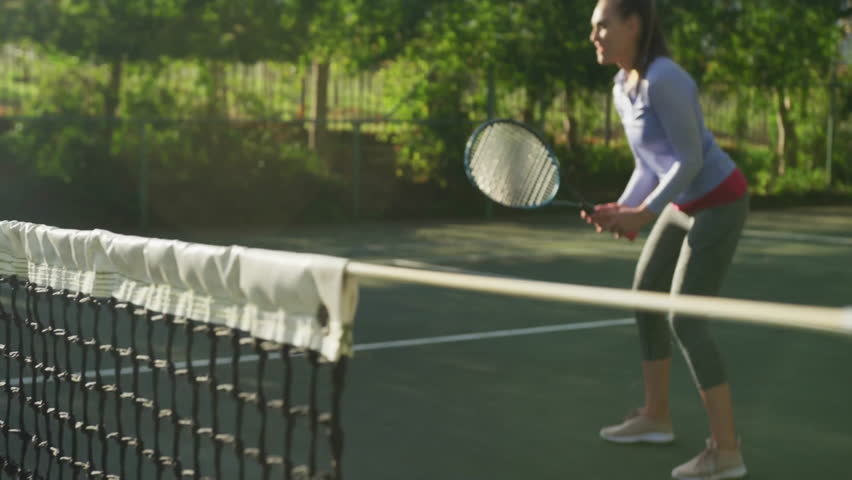 woman playing tennis near net on tennis court lines with VIBES graphic overlay promoting health. Athletic, competition, outdoor, vibrant, fitness, active, leisure