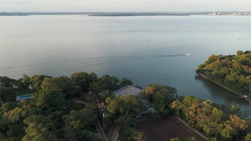 An orbiting drone shot over the Paraná River with a boat in the middle.