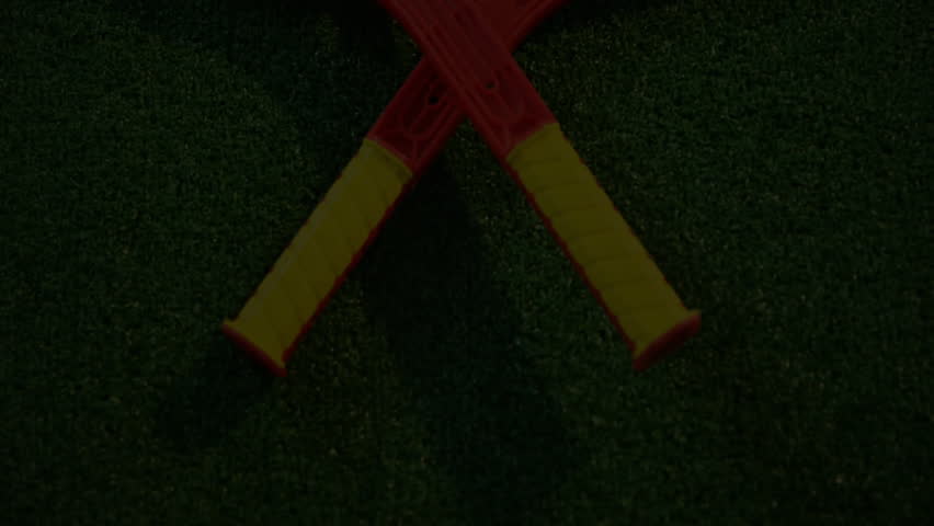Red paddle rackets forming V shape on green turf while glitch lines, skull and code scrolling. Sport equipment, digital art, modern design, esports, vibrant, gaming, technological