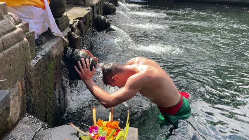 Close-up of man performing traditional water purification ritual at Tirta Empul Temple in Ubud Bali, Indonesia. Spiritual moment ideal for religion, culture, and travel content.