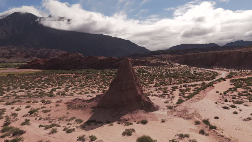 Drone footage of the natural Obelisco in Quebrada de las Conchas, Salta Argentina, a mountain in the horizon and clouds.